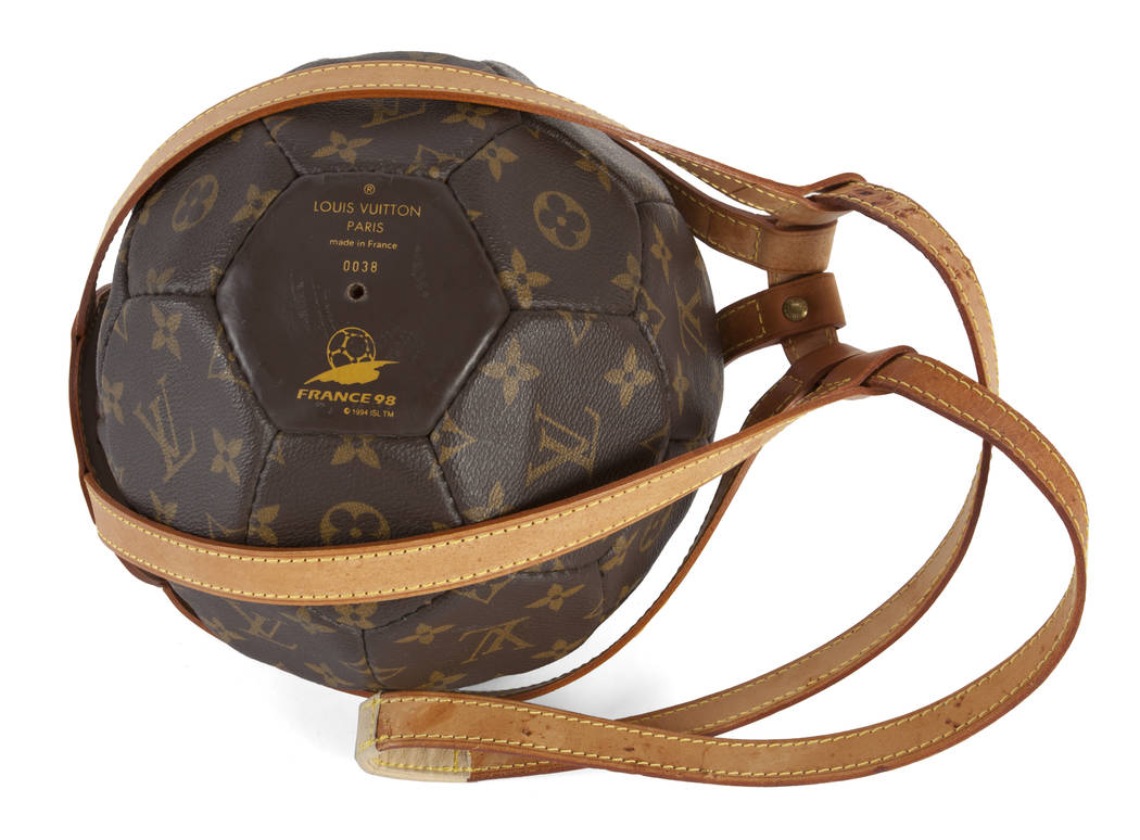 A limited edition monogrammed soccer ball with leather holder made by Louis  Vuitton for the World Cup in France in 1998. Together with a copy of  Rebonds, a limited edition Louis Vuitton