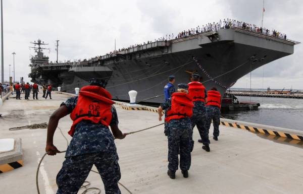 Navy shore crew haul in lines as the nuclear-powered aircraft carrier USS Abraham Lincoln arriv ...