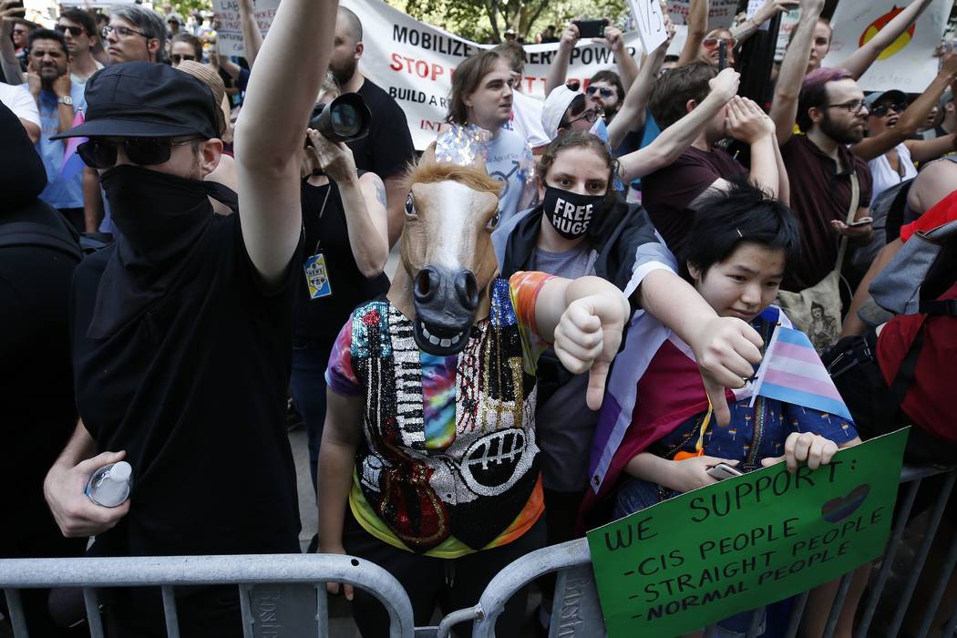 Counterprotesters, including one wearing a horse mask, line the route of the Straight Pride Par ...