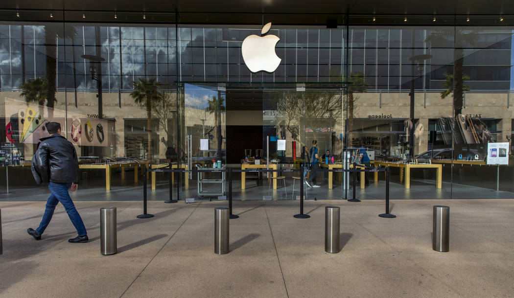 A passerby looks to the Apple Store now closed until March 27th at