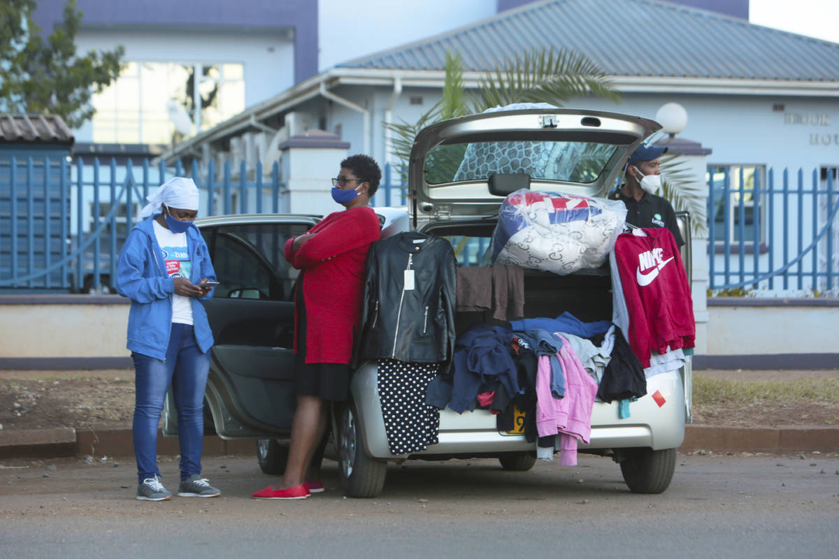 People sell clothes displayed on their car by the side of a busy road in  Harare, Zimbabwe, Tues …