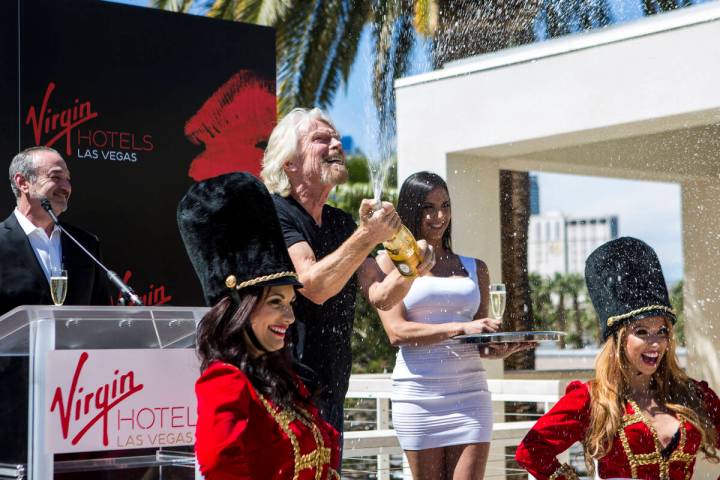 Virgin Group founder Sir Richard Branson pops a champagne bottle following a press conference a ...